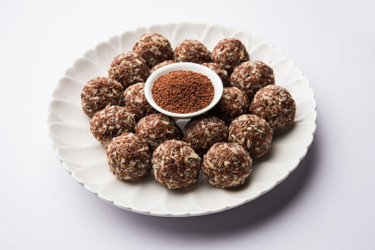     Homemade halim ladoos made with garden cress seeds and nuts, served on a white plate with dry halim seeds.