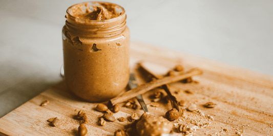 Natural peanut butter in a glass jar with roasted peanuts