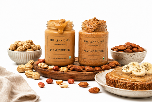 The Lean Oven peanut butter and almond butter jars with banana toast, peanuts, and almonds showing a protein-rich nut butter comparison.
