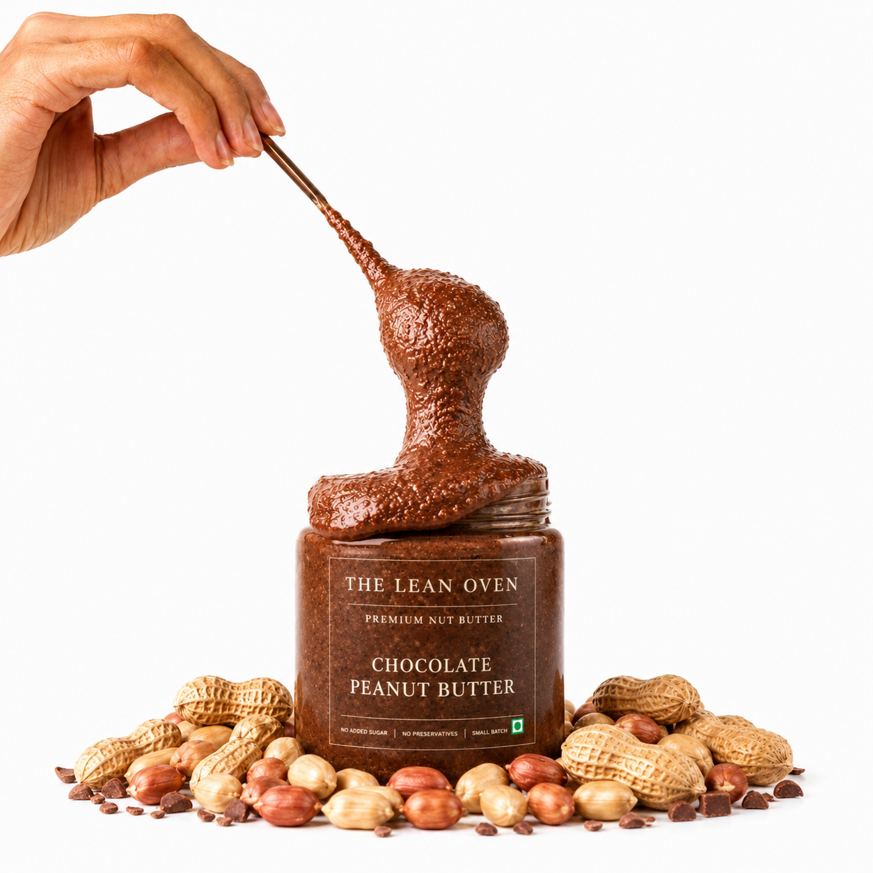 Jar of The Lean Oven Chocolate Peanut Butter with a hand scooping it out, surrounded by peanuts.