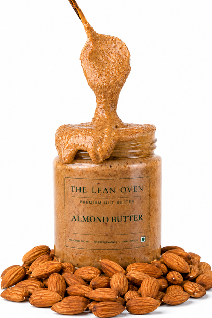 Jar of almond butter with a spoonful above, surrounded by almonds on a white background