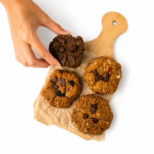 Hand reaching for a cookie on a wooden board with other cookies